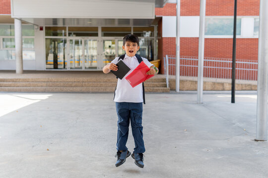 Excited schoolboy jumping with books in hand