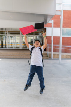 Excited schoolboy celebrating with notebooks in hand