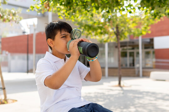 Boy enjoying a drink outside school building