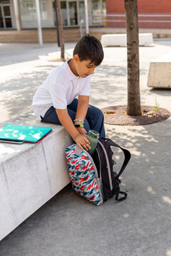 Boy sitting outdoors with school supplies