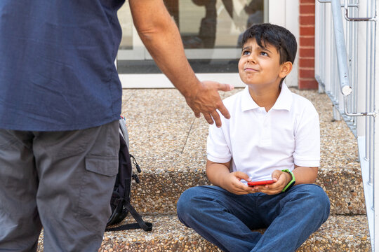 Boy sitting on school steps with phone in hand