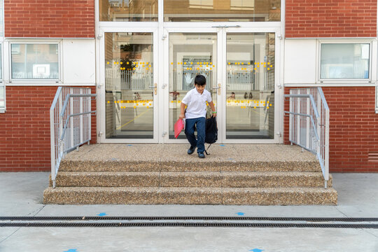 Boy leaving school building in early morning light
