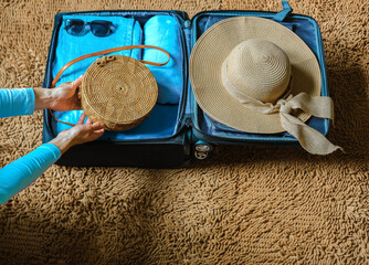 Close up woman packing suitcase to vacation  getting ready to travel trip. Concept of summer vacation trip. Brown blue colors.  © Iryna