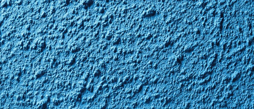 A bright blue textured wall surface with raised, irregular patterns under focused lighting