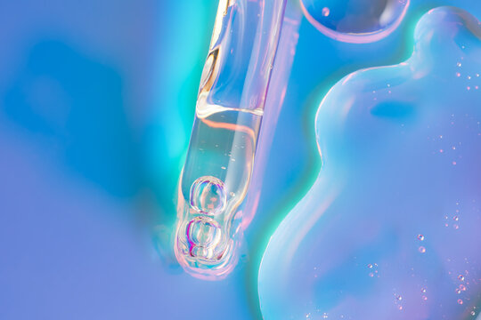 Cosmetic serum drop with pipette in neon blue light