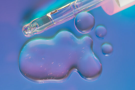 Cosmetic serum drop with pipette in neon blue light