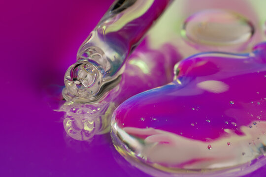 Neon cosmetic serum dropper with glossy gel texture closeup