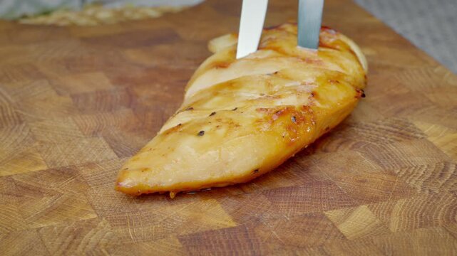 Resting Grilled Chicken Breast On Wooden Board, Sharp Knife Slicing Tender White Meat, Juices Visible, Careful Technique For Even Portions And Healthy Meal Prep