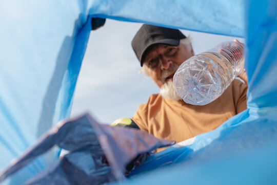 Volunteer collecting plastic bottle during outdoor cleanup