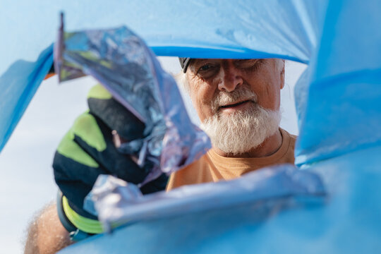 Senior volunteer collecting plastic waste for beach cleanup