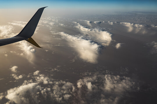 Airplane wing above clouds in warm evening light view