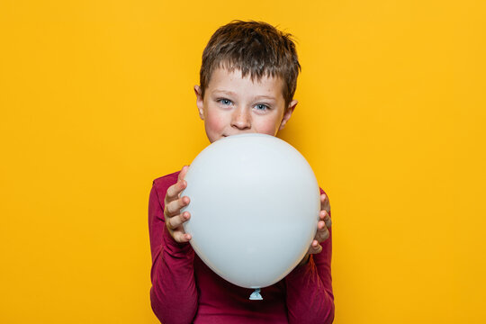 Child holding white balloon against bright yellow background