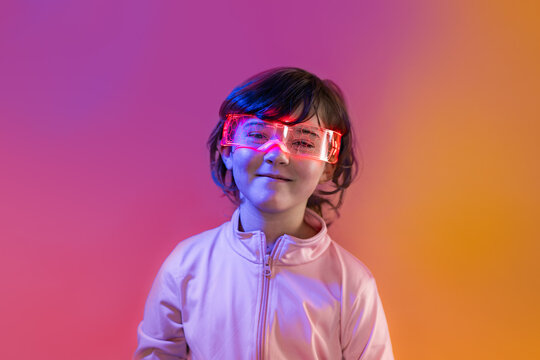 Kid wearing LED glasses in neon studio, future tech vibe