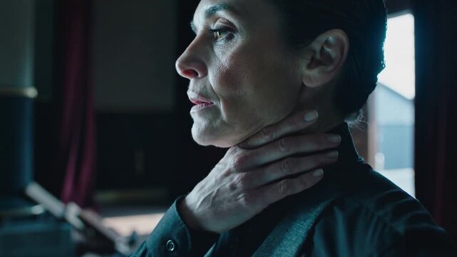 Adjusting Senior woman preparing for show, touching collar and throat on stage, smoothing grey vest
