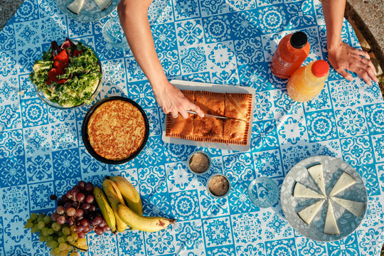 Summer picnic table with woman cutting empanada outdoors