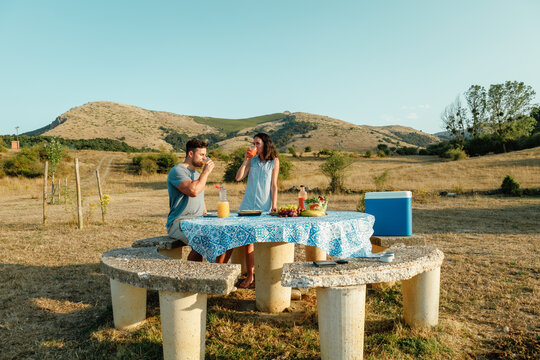 Couple enjoying summer picnic with gazpacho and juice outdoors