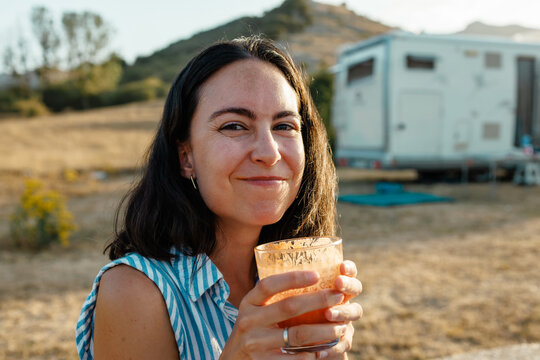 Woman enjoying gazpacho at summer picnic near camper