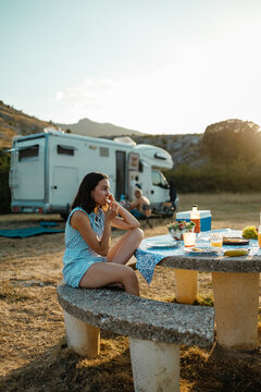 Woman enjoying summer picnic by camper van at sunset