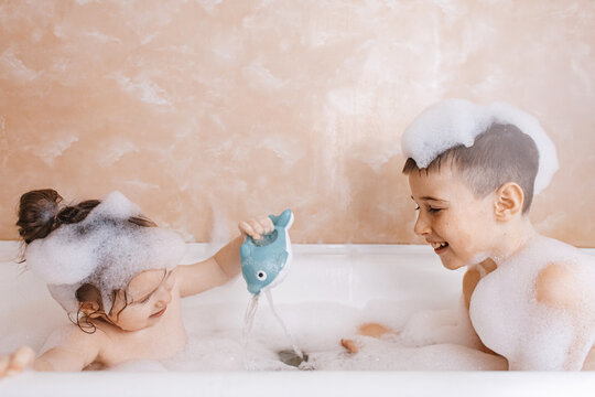 Siblings having fun in a bubbly bath
