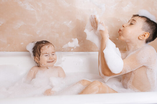 Siblings enjoying a fun bubble bath with foam