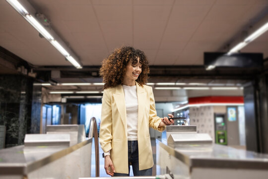 Hispanic woman using smartphone at train station