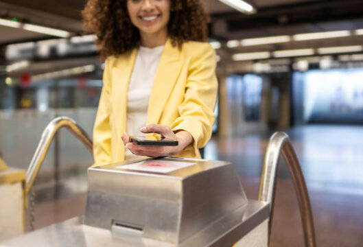 Hispanic woman using smartphone at subway gate