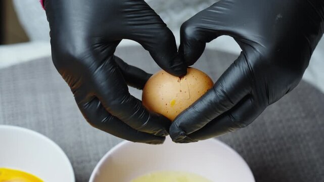 Frying the Perfect Egg. Precise technique used to crack eggs into bowls. Chef carefully cracks eggs into bowls for baking with precision