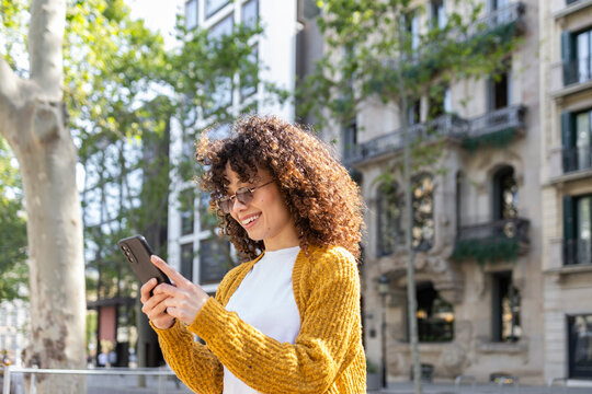 Hispanic woman enjoying city life with technology