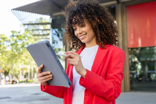 Hispanic woman using tablet outdoors