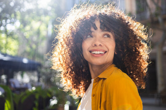 Smiling woman with curly hair enjoying outdoor lifestyle