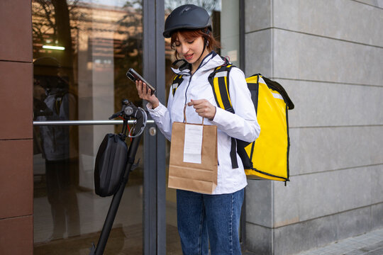 Female delivery rider checking order at building door