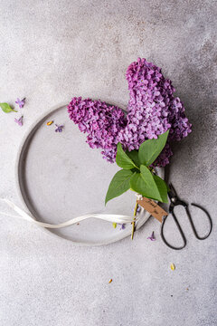 Bouquet of lilac flowers with ribbon on gray plate