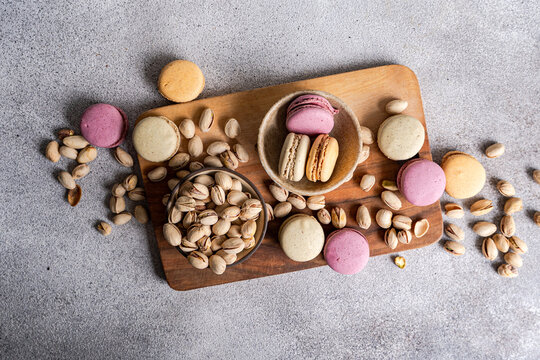 Assorted macarons with pistachios on wooden board