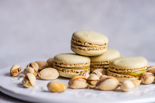 Pistachio macarons with scattered nuts on plate