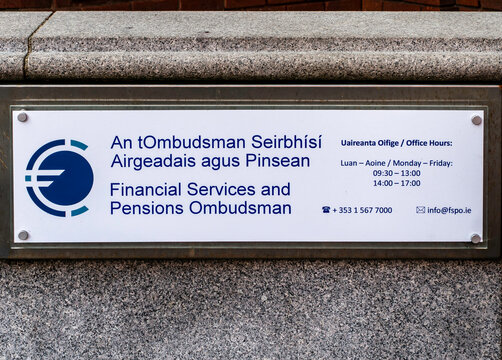 Financial Services and Pensions Ombudsman sign at Lincoln Place, Dublin, Ireland. Bilingual Irish and English plaque on a granite stone wall.