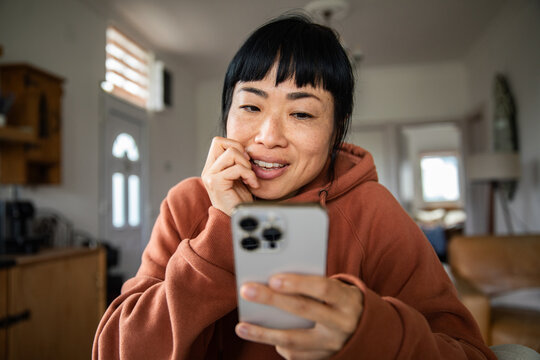 Smiling woman using smartphone at home