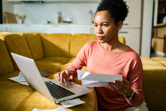Serious woman managing finances on laptop at home