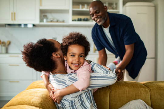 Parents hugging smiling child in modern kitchen