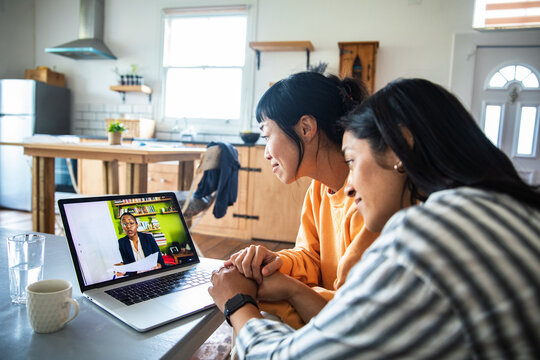 Two women video calling a consultant in home kitchen