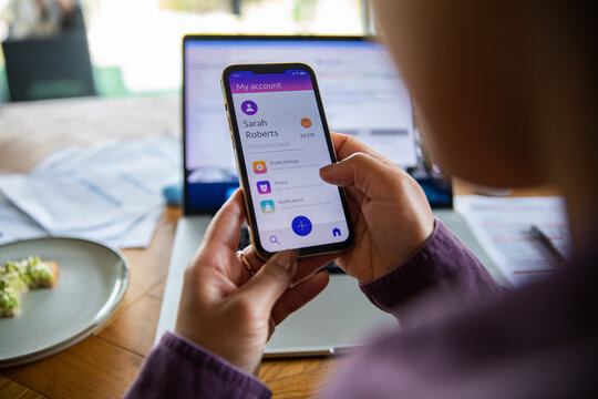 Person checking mobile banking app at home desk