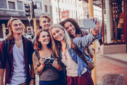 Happy young travelers taking selfie on city street