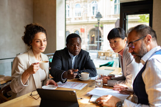 Diverse business professionals meeting at coffee shop with tablet