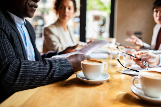 Coworkers discussing documents over coffee at a cafe