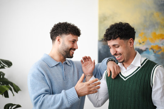 Two young men share a laugh and a moment of connection, their smiles bright and genuine.