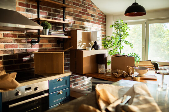 Household moving boxes in sunny brick kitchen