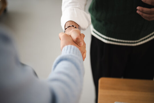 Two people shake hands, signifying agreement and partnership in a professional setting.