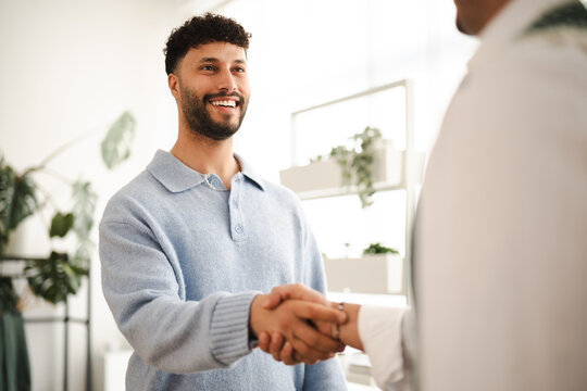 Two men shake hands in a bright, modern office setting, signifying a successful business agreement or partnership.