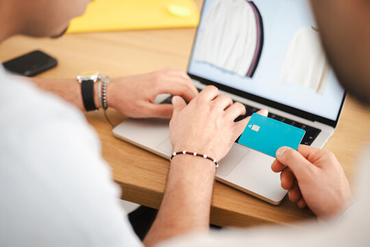 A person uses a laptop and a debit card to make an online purchase of clothing.