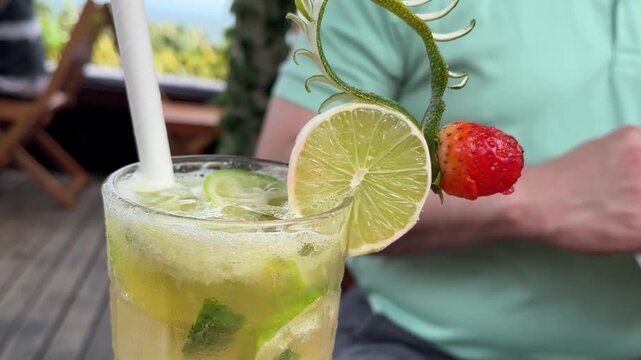 Refreshing tropical cocktail with editable lime and strawberry garnish, using sustainable straws in Brazil Rio de Janeiro