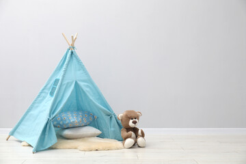 Wigwam, toy bear and pillows in child's room, space for text © New Africa